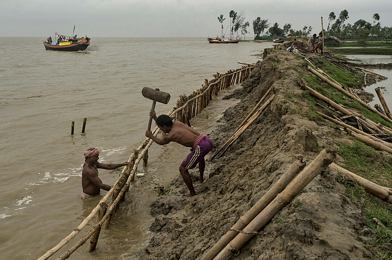 Two men building embankments by sea